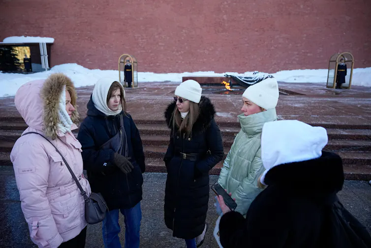 Women in white hats gather and talk.