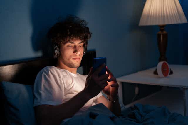 Man looking at phone screen in bed