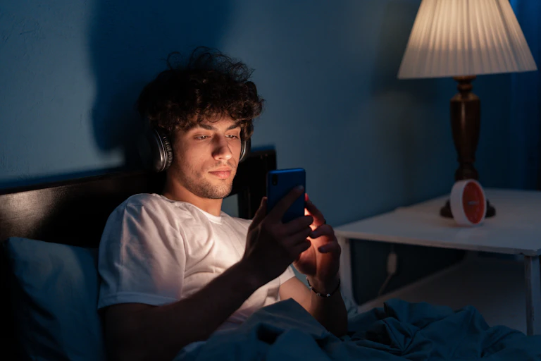 Man looking at phone screen in bed