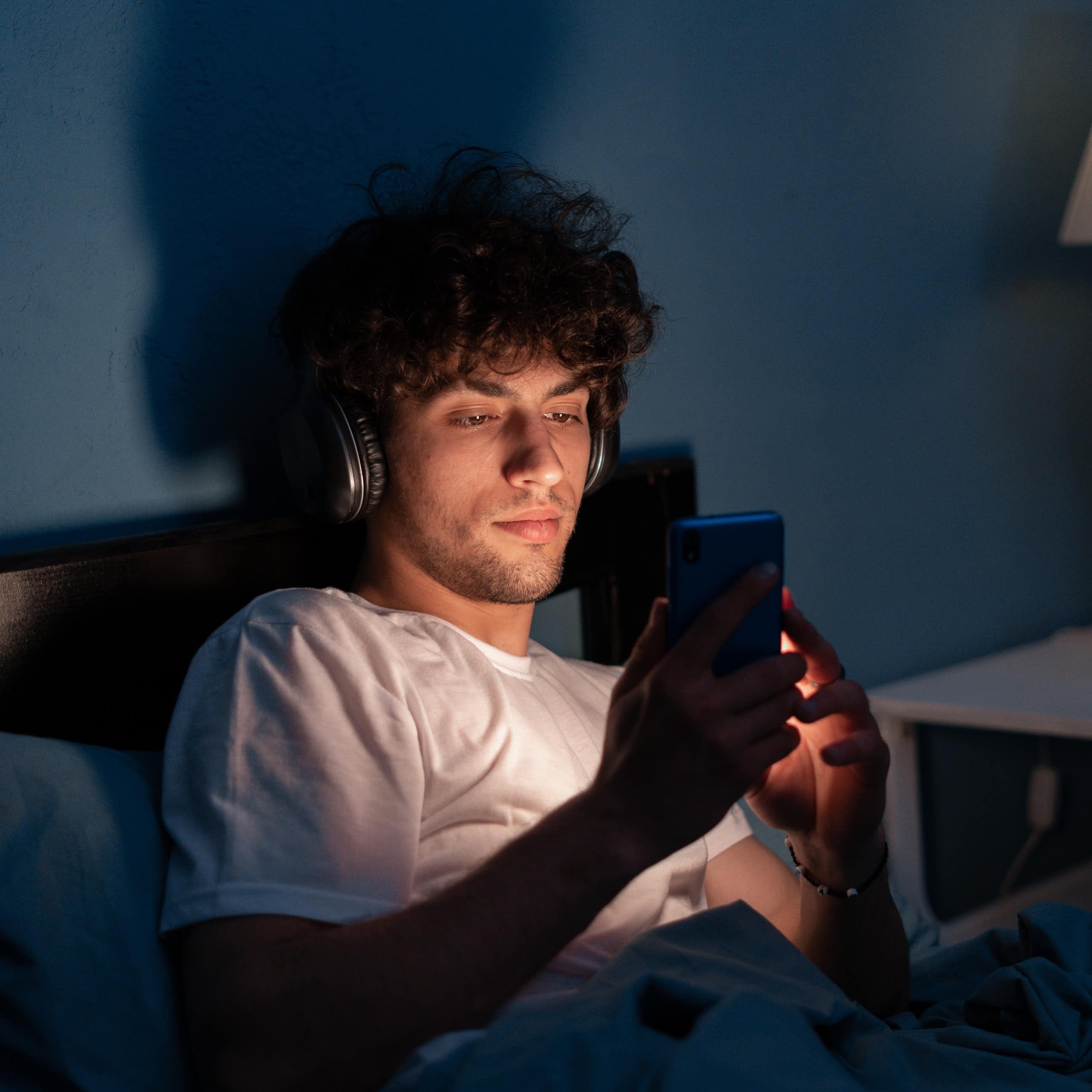 Man looking at phone screen in bed