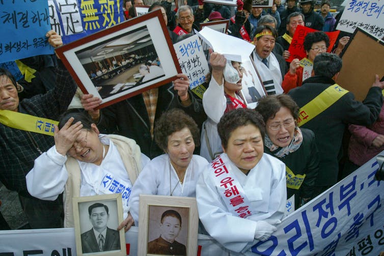 Elderly Korean women cry, scream and hold photos of lost loved ones during a protest march.