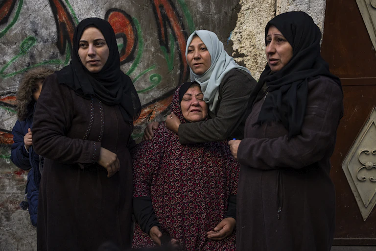 Four women in headscarves. One comforts another.