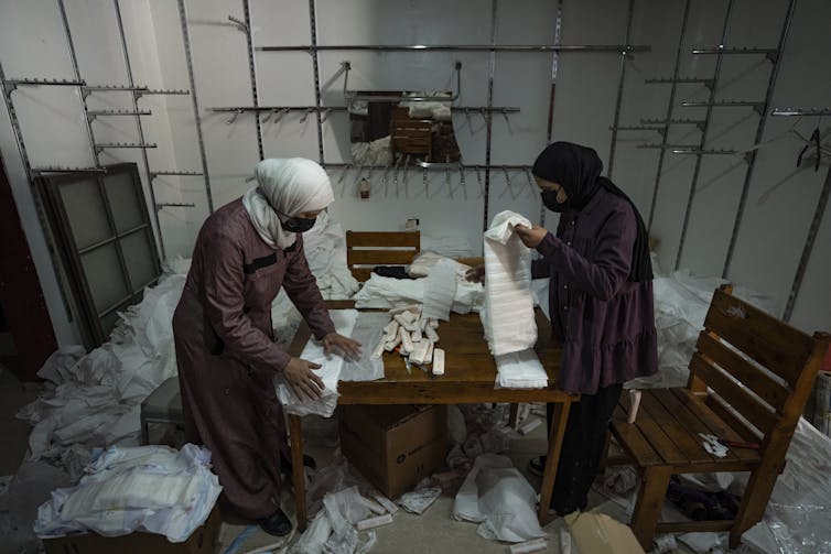 Two women wearing face masks in a room handling diapers.