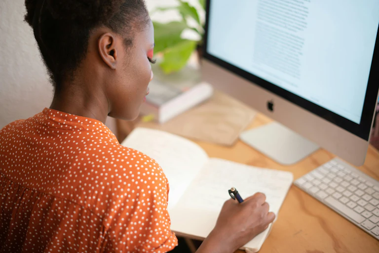 Woman writes in notebook while working from home