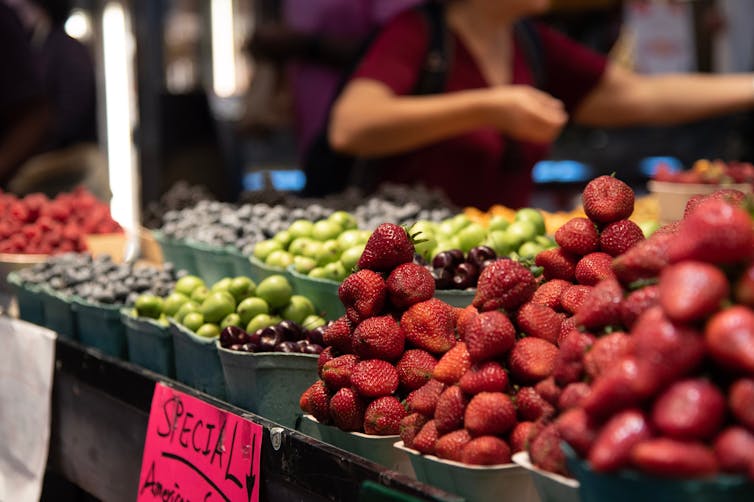 Piles of strawberries and cherries on sale at an indoor market.
