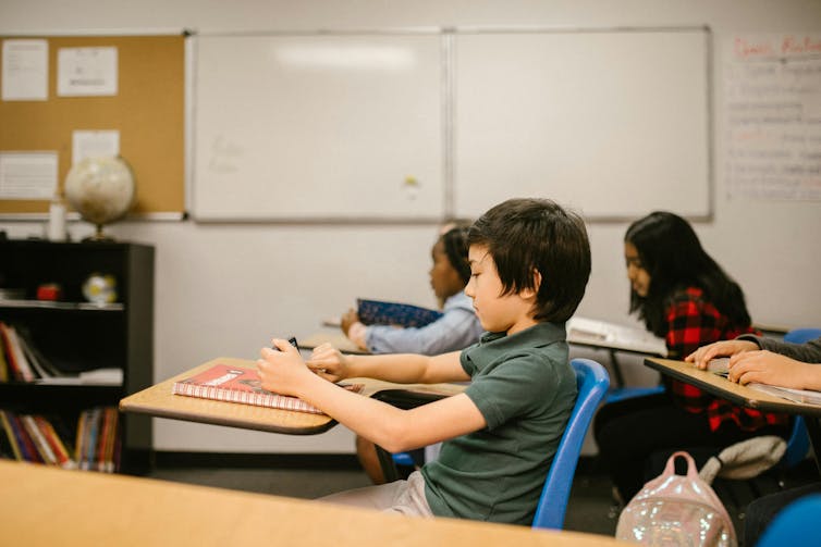 A young boy looks at his smart phone in class.