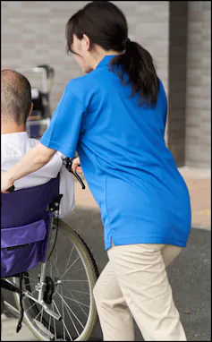 A female care worker helps a person in a wheelchair