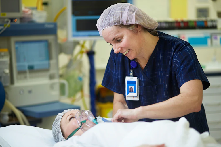Female nurse smiles at patient on a hospital bed