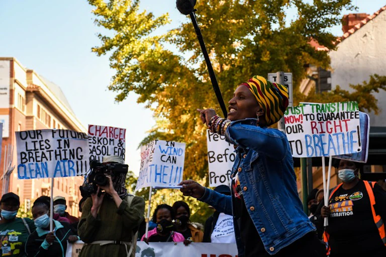 A protest outside a court room with people holding placards saying 'our future lies in breathing clean air'