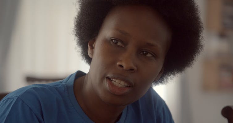 An African woman with natural hair is shown in close-up as she talks.