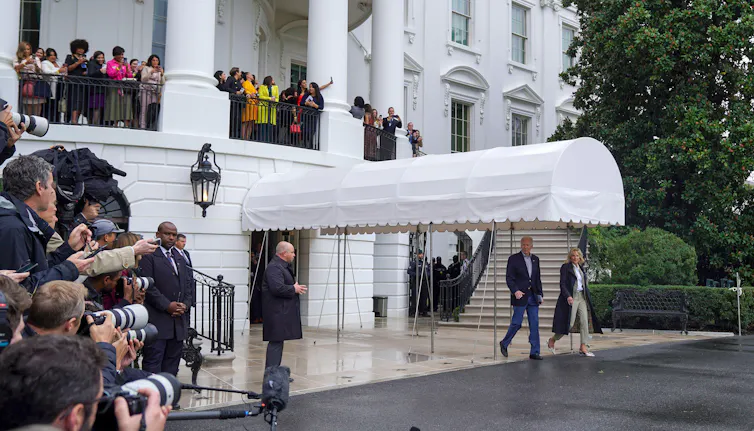 Jill and Joe Biden in front of a white awning with influencers looking on.