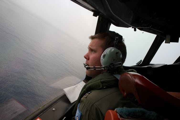 A Royal Australian Air Force flying officer looks out for signs of MH370 during a search in bad weather on 24 March 2014.