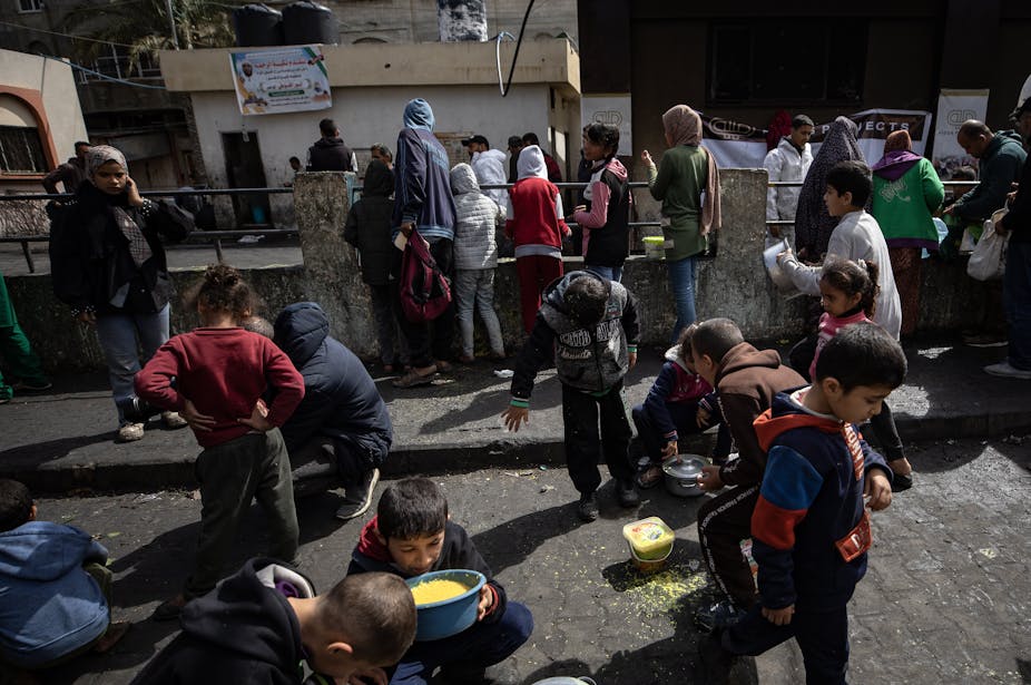 Palestinians gather to eat food in the Rafah refugee camp, Gaza, March 2024.