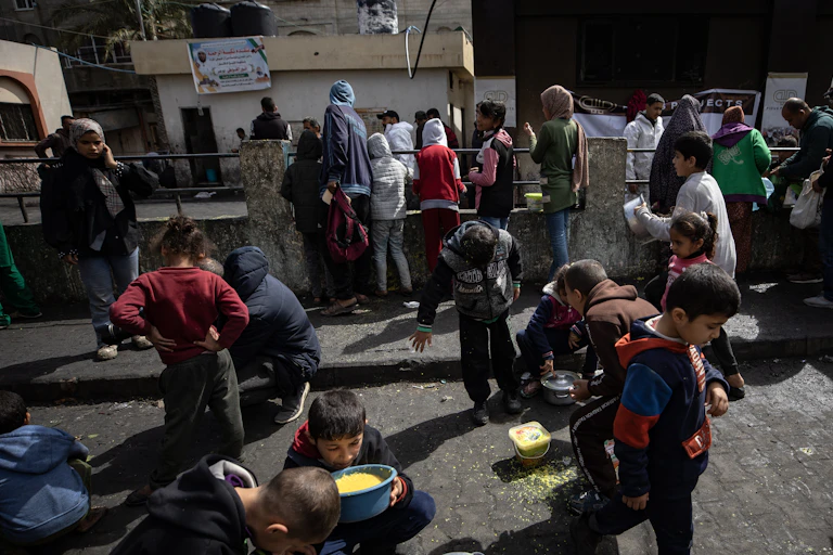 Palestinians gather to eat food in the Rafah refugee camp, Gaza, March 2024.