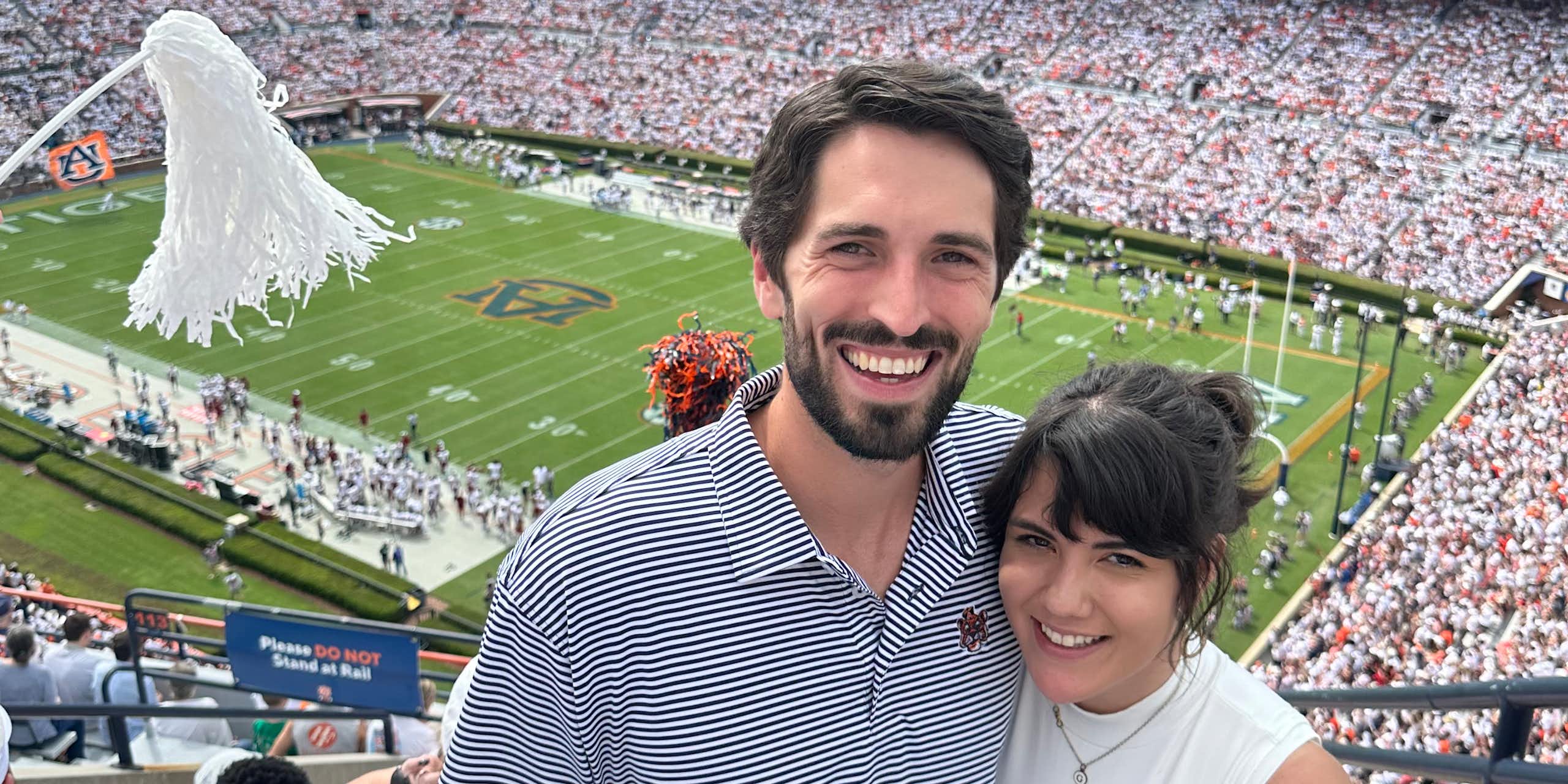 A smiling couple with a football stadium in the background.