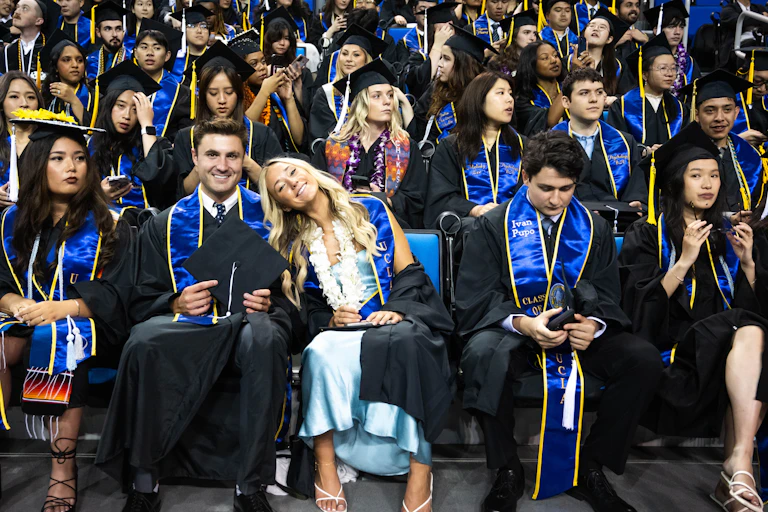 College graduates at a ceremony in their caps and gowns.