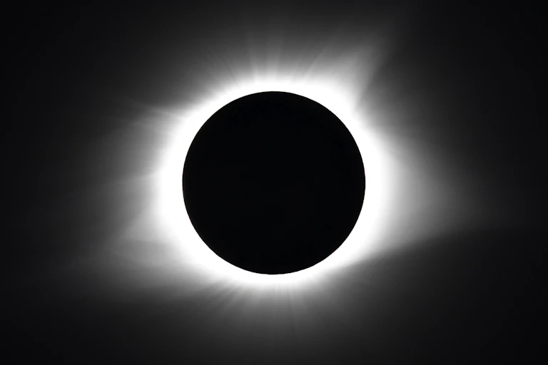 The Moon blocking the Sun, with just a circle of light visible, against a dark background.