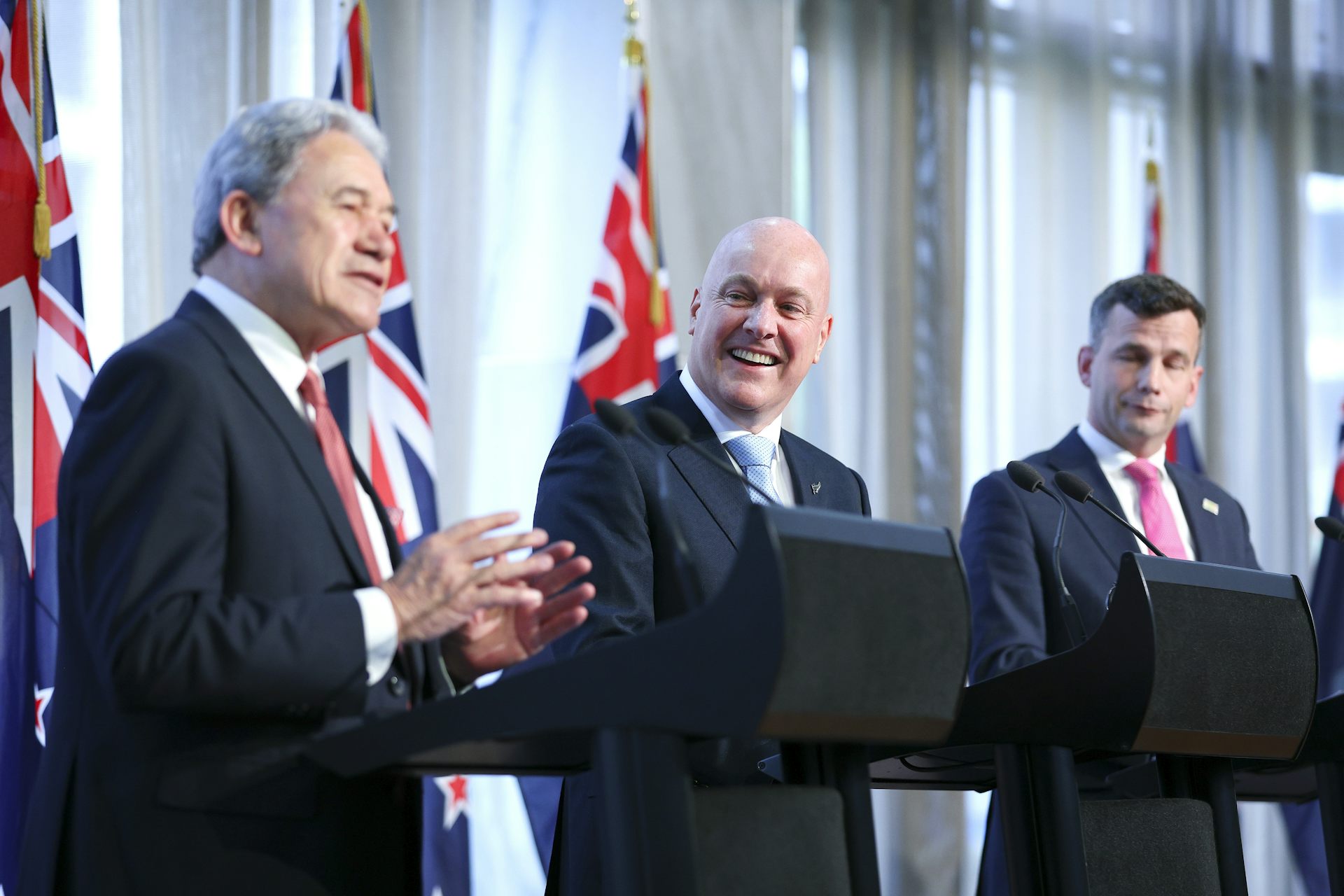 Three men talking in front of podiums