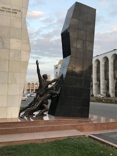 A monument shows two people pushing a structure.