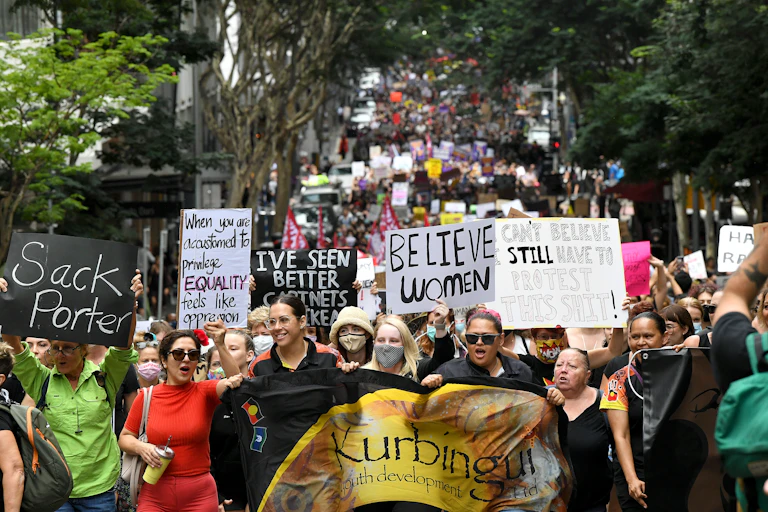 Mulheres carregando faixas com dizeres feministas se manifestando em uma rua