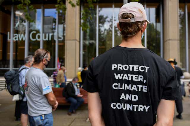 A protest slogan on a black t-shirt reads "Protect water, climate and country" as Gomeroi people and supporters participate in a rally outside the Federal Court of Australia in Sydney