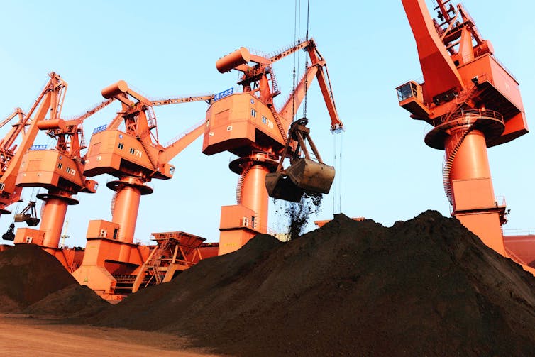 Large grab buckets unload iron ore from a cargo ship in China