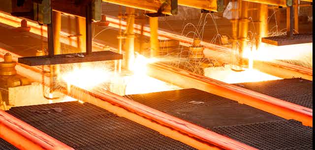 Red hot steel passes along a conveyor in a steel mill
