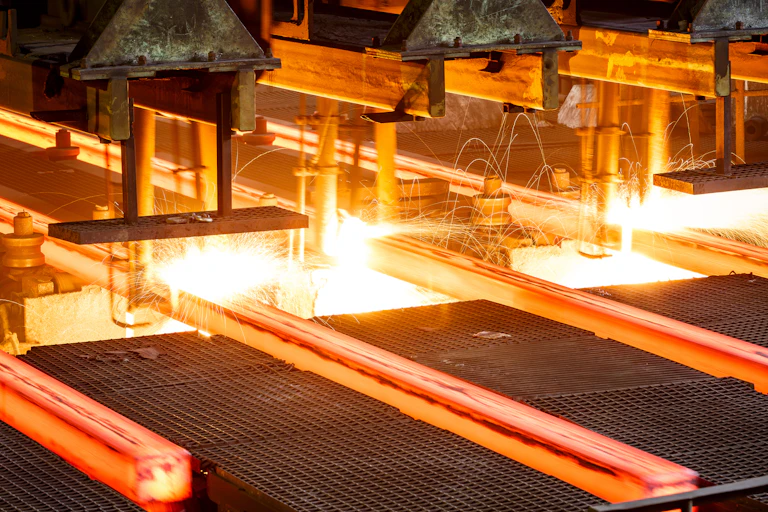 Red hot steel passes along a conveyor in a steel mill