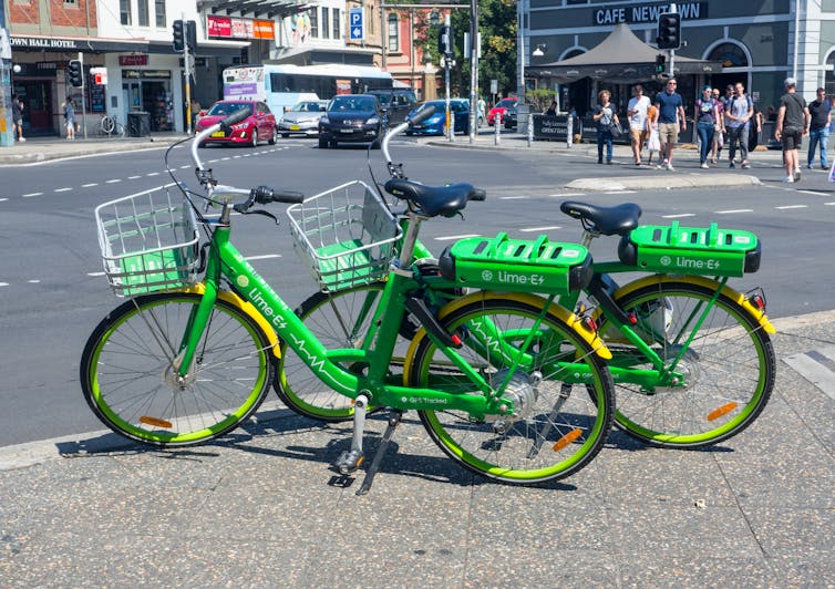 Two e-bikes parked at the edge of a city street