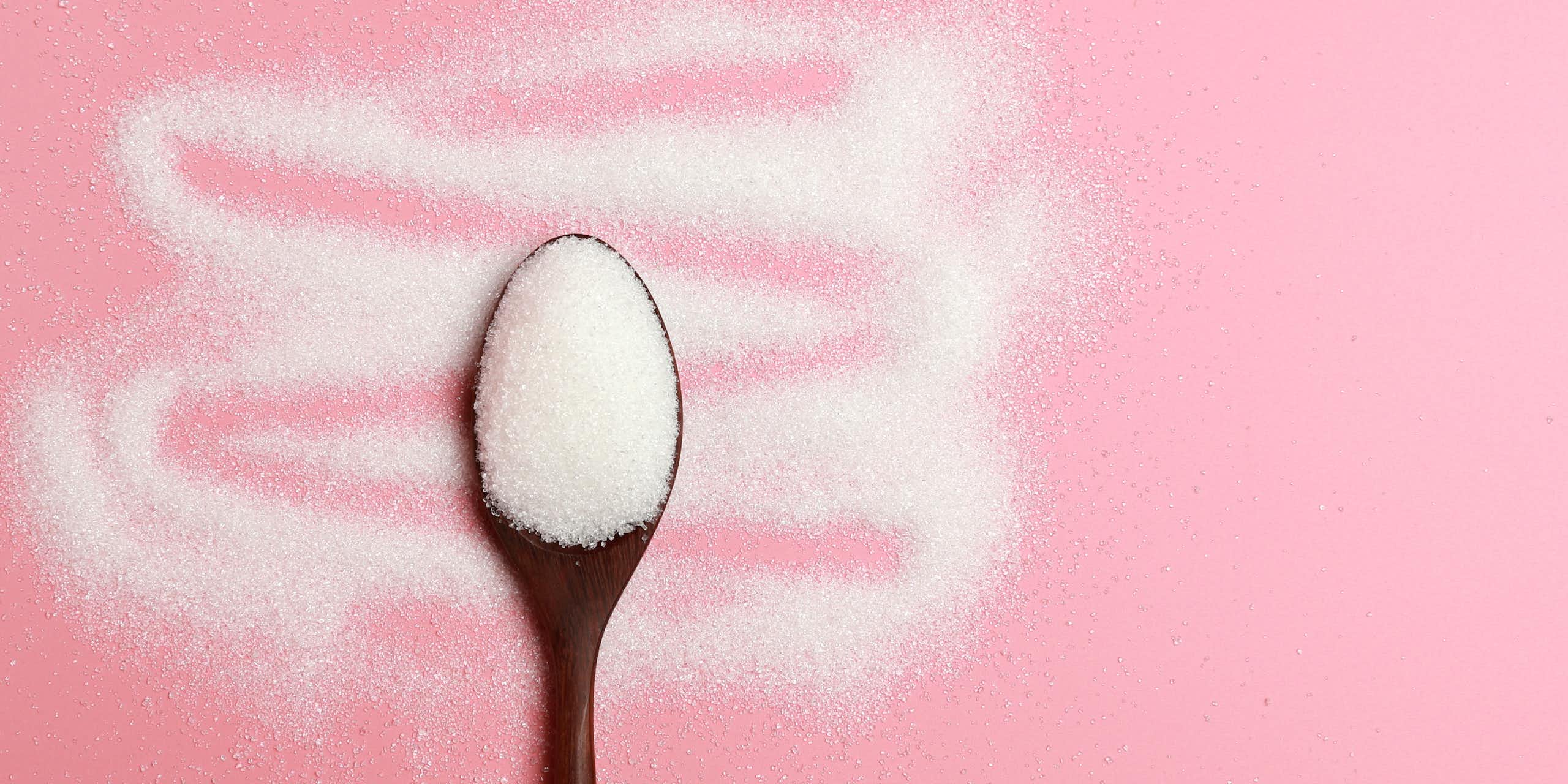 A spoonful of sugar on a pink background.