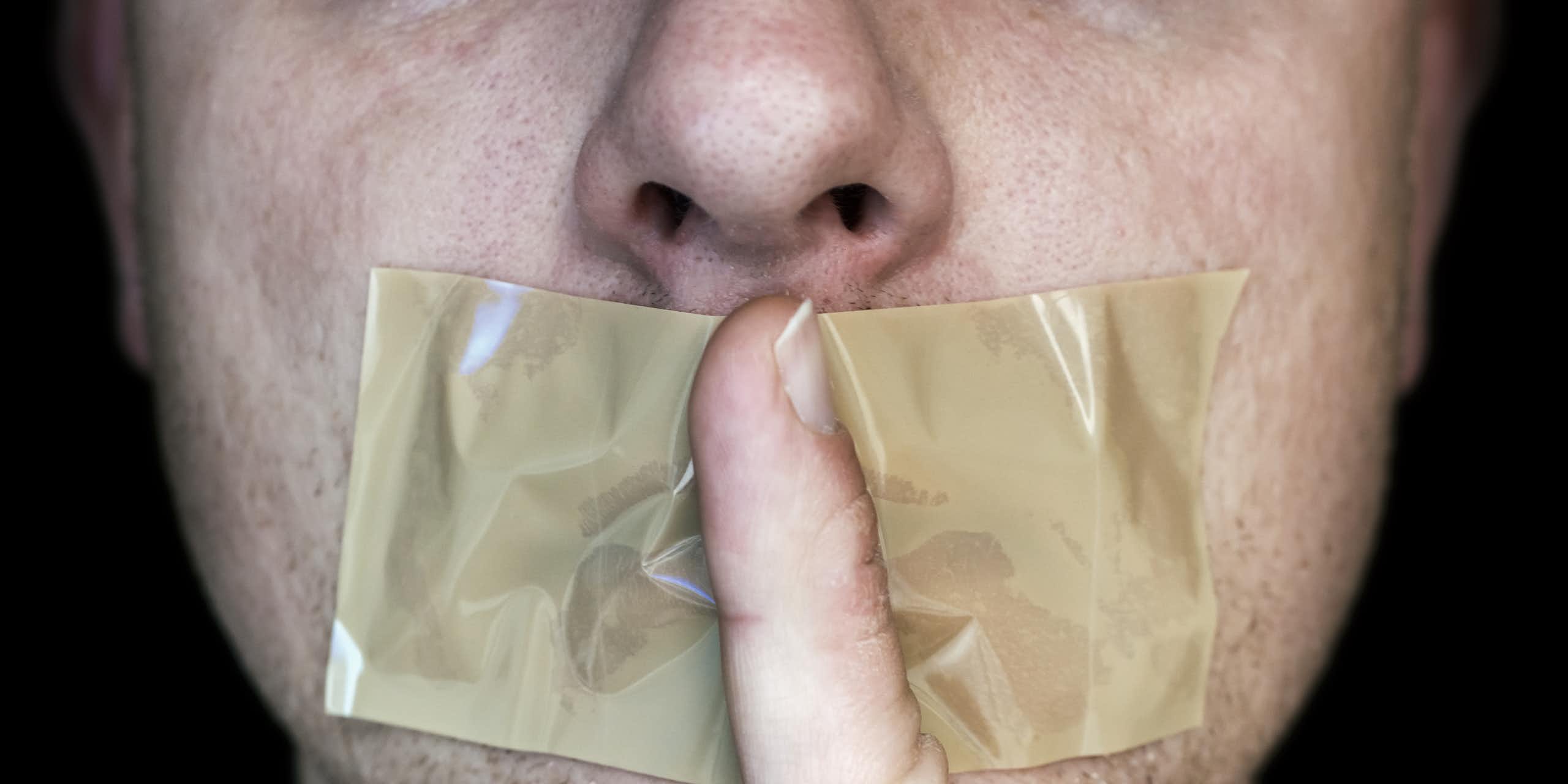 Mouth coverdd in tape, forefinger held in front