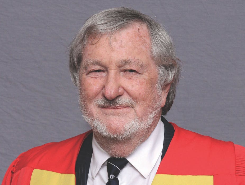 Head and shoulders portrait of a grey-haired man in academic gown