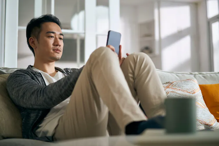 Man sitting on the sofa looking at his phone.