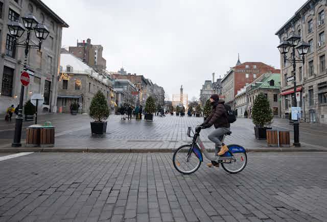 Pedestrians and cyclists move about on cobble-stoned streets.