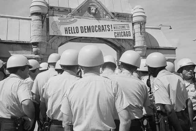 A welcome to Democrats on the entrance to a convention center, with helmeted police crowded in front.