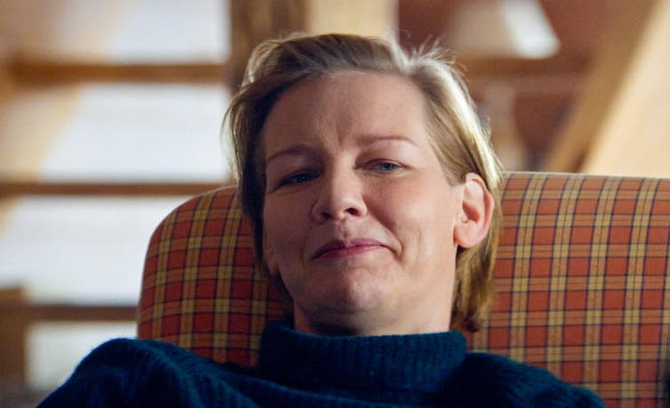 A woman sitting back in a chair smiling.