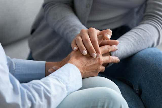 Close up shot of a younger person holding the hands of an older person