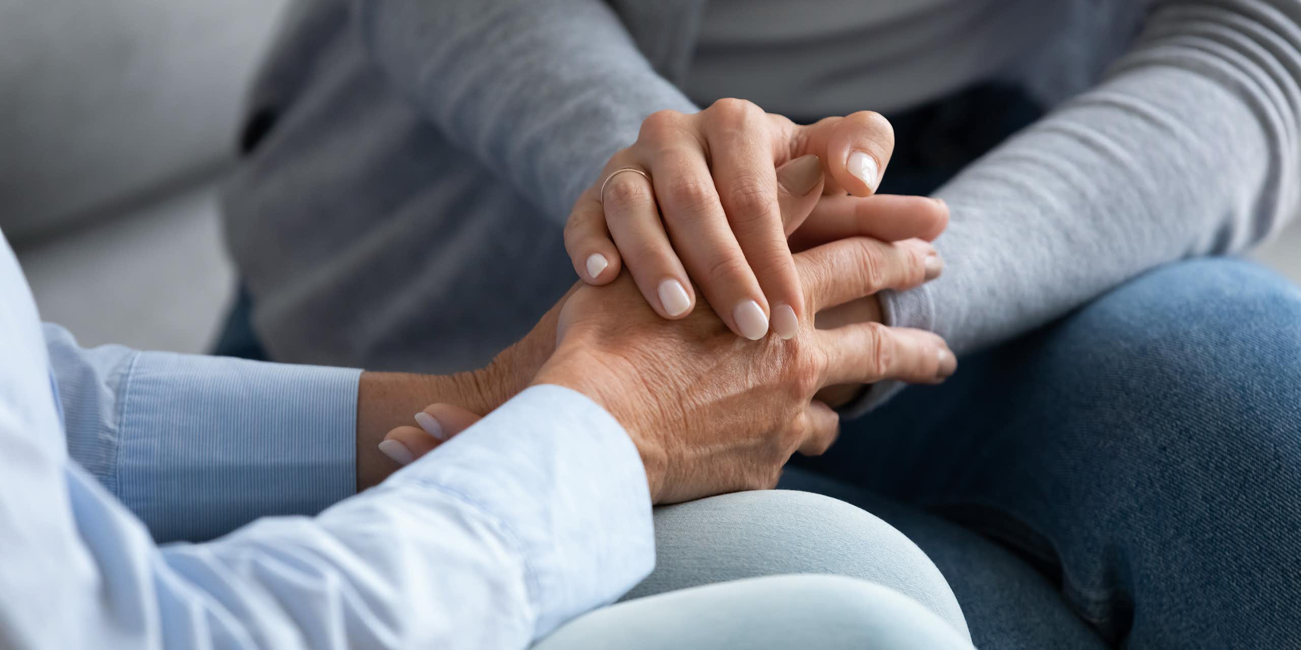 Close up shot of a younger person holding the hands of an older person