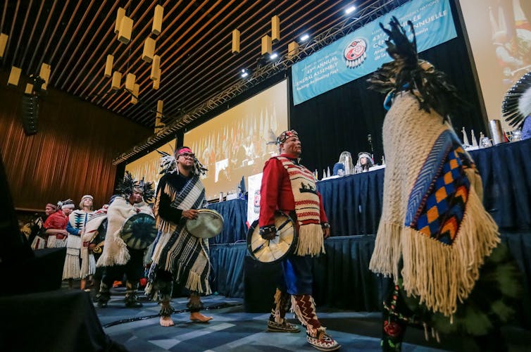People in traditional dress on stage at the opening ceremony of the Assembly of First Nations in Vancouver