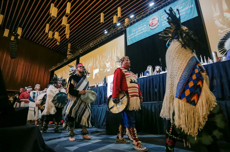People in traditional dress on stage at the opening ceremony of the Assembly of First Nations in Vancouver