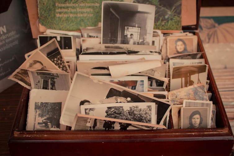 A drawer filled with old black and white photos appears to overflow.