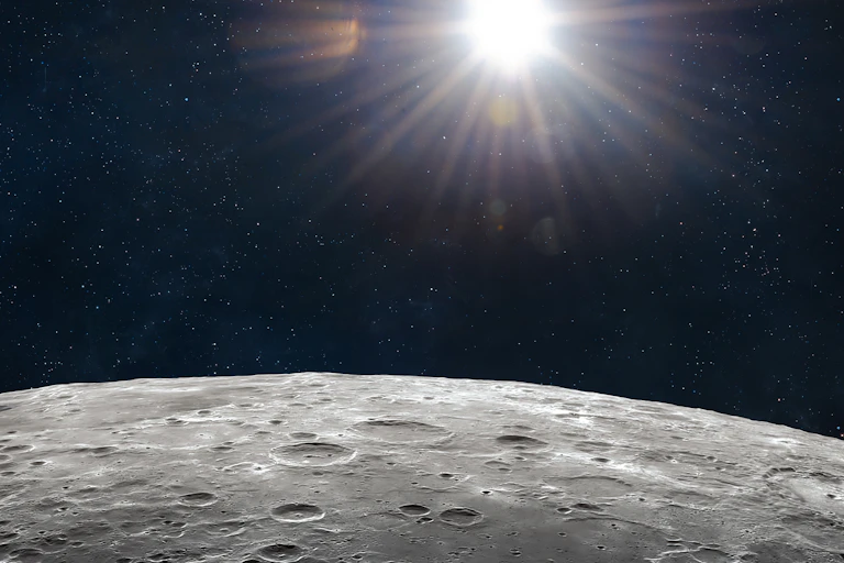 Superficie de la Luna con el sol al fondo.