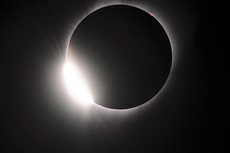 a black circle surrounded by a white halo of light against a dark background