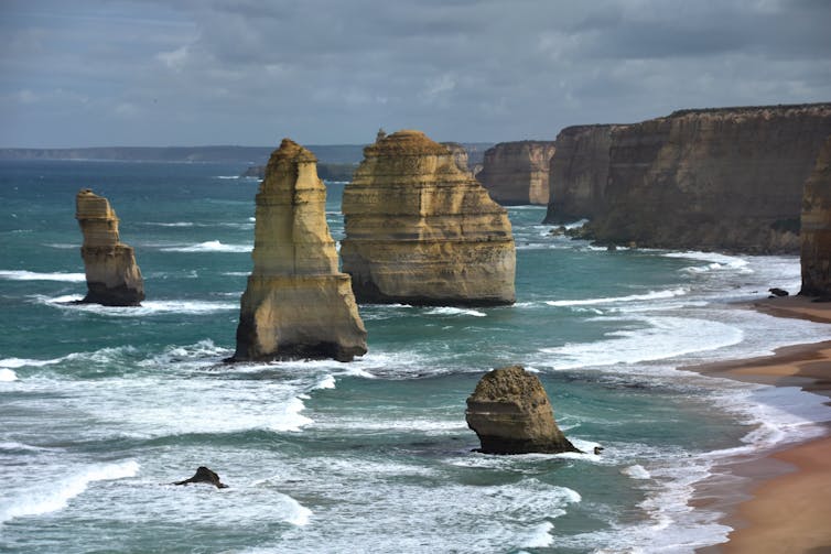 A photo shows rocky pillars and cliffs in the ocean.