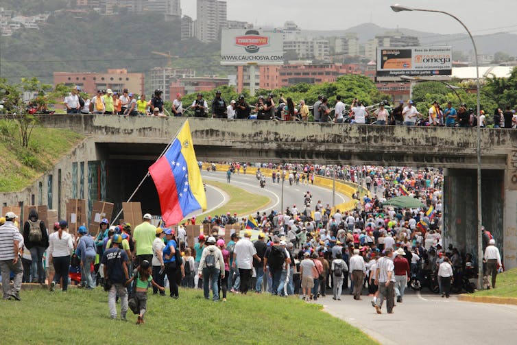 A crowd of Venezuelan protestors blocking a highway.