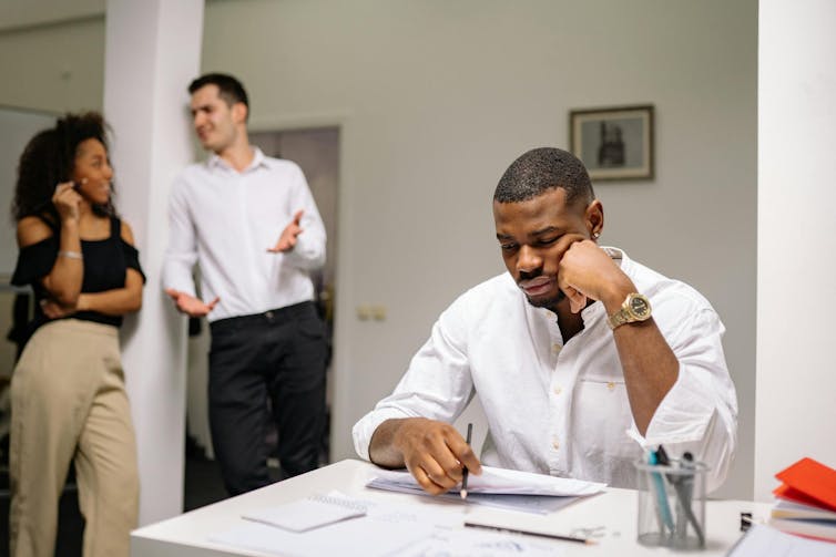 Man working being distracted by two people talking nearby