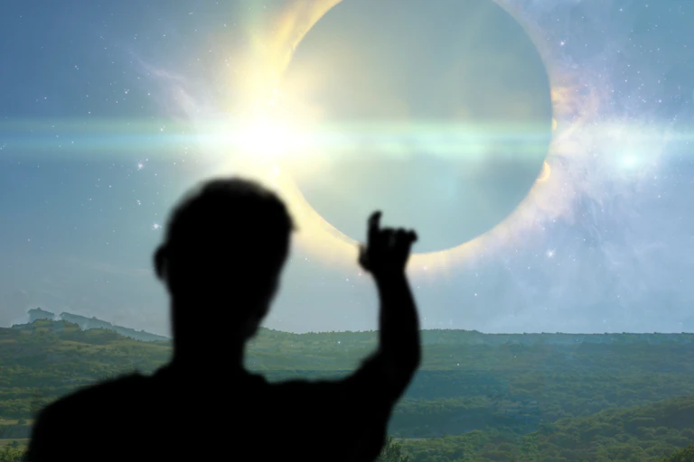 a silhouette of a man pointing at the sun
