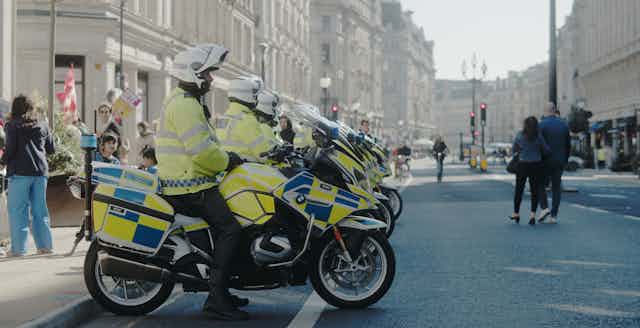 View from the side of a row of Met Police officers lined up on police motorbikes