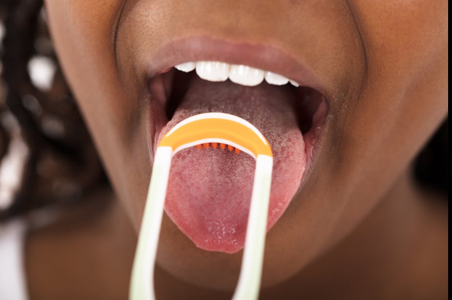 A woman uses a tongue scraper.