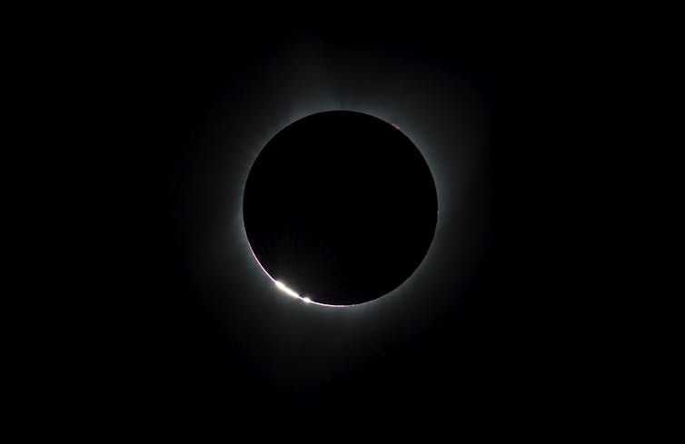 un cercle noir entouré d’un anneau lumineux plus épais dans le quadrant inférieur droit